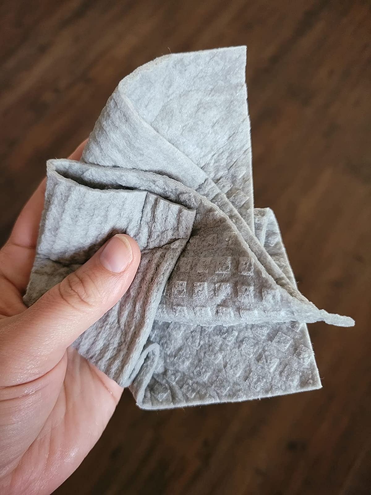 a reviewer scrunching a gray swedish dishcloth