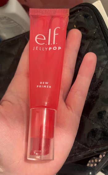 A manus  holds a conduit  of e.l.f. Jelly Pop Dew Primer, highlighting its compact, travel-friendly design