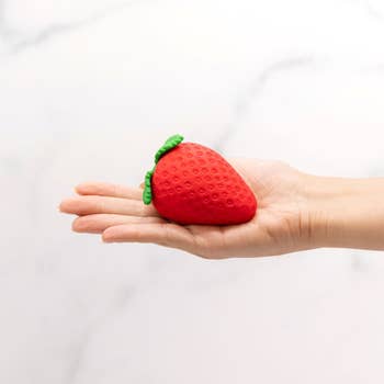 Hand holding red and green strawberry vibrator