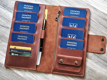 The open passport holding filled with credit cards, passports, and a pen in tan