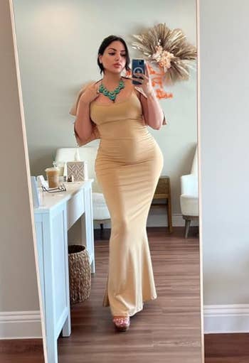 reviewer in an off white colored form fitting maxi dress