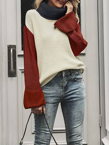 a model wearing the red, white, and gray turtleneck with jeans