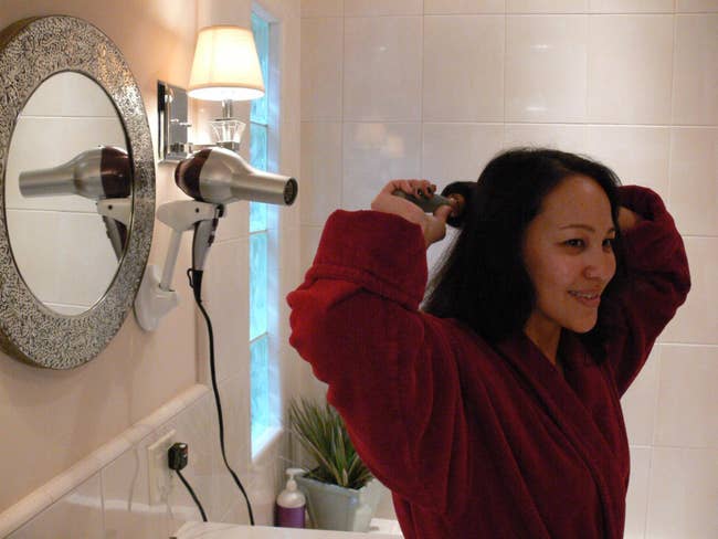 reviewer showing how the hair dryer holder makes it easy to blow dry their hair