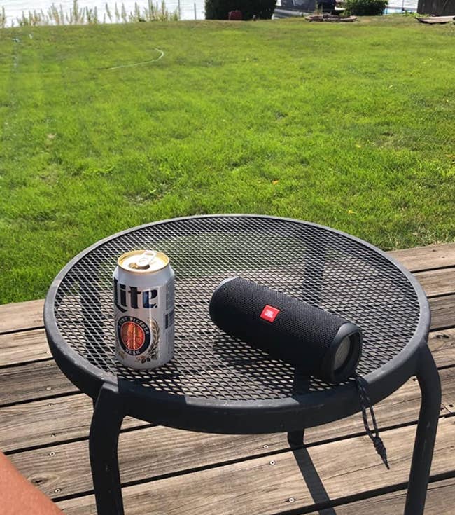 reviewer photo of the black speaker sitting on a table outside next to a beer can