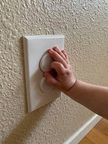 reviewer showing a child's hand on the babyproof outlet plug