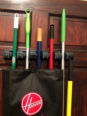 Reviewer photo showing close up of organizer holding brooms and mops 