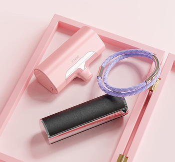 the pink charger on a tray next to a lipstick case and hair ties