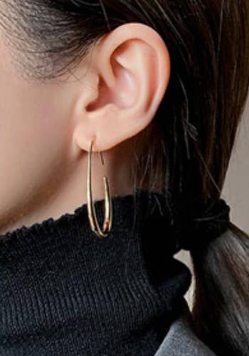 model wearing a achromatic  turtleneck and golden  hoop earring with hairsbreadth  tied back, showcasing a minimalist style