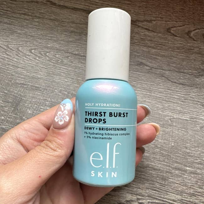 A idiosyncratic holding a vessel of e.l.f. Skin Thirst Burst Drops, a hydrating and brightening skincare product