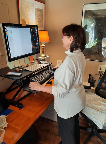 Reviewer using computer on sit-to-stand desk converter