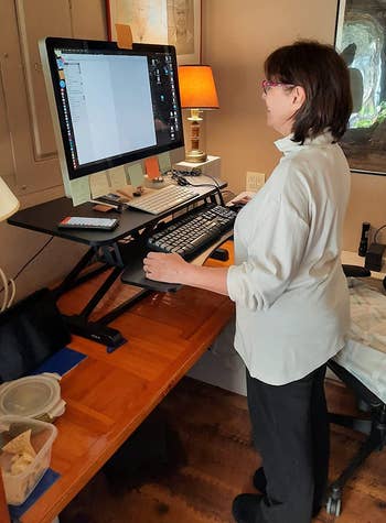 Reviewer using computer on sit-to-stand desk converter