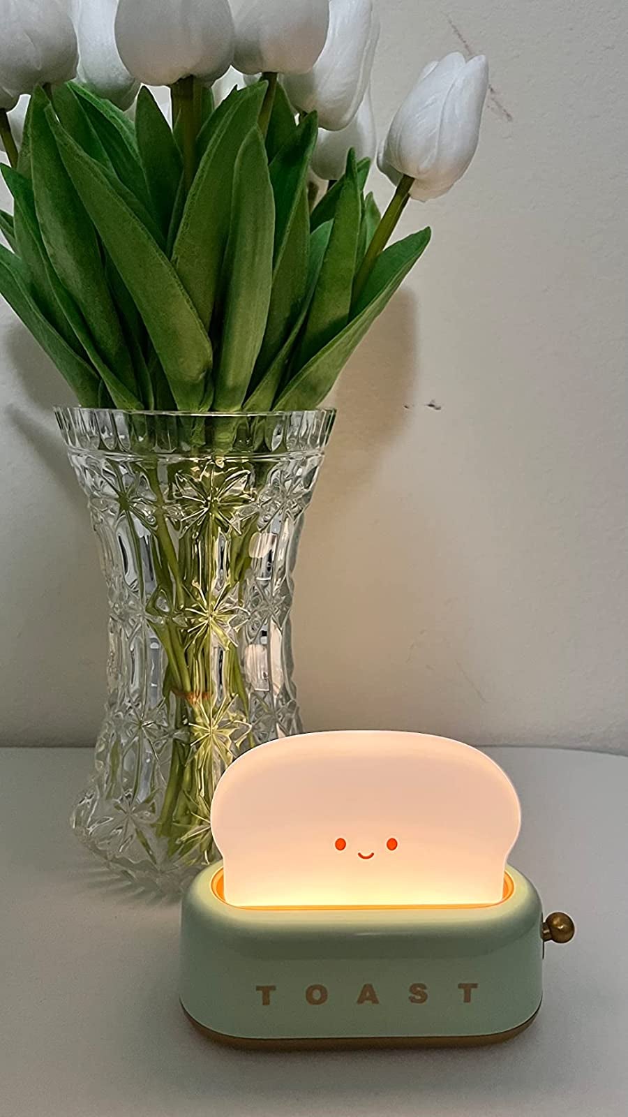 A reviewer's green toast light lit up on a table next to a vase of flowers