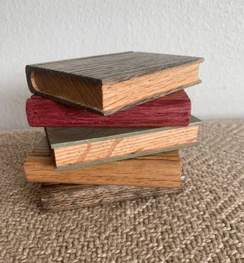 five wooden book coasters in different colors stacked on top of each toher