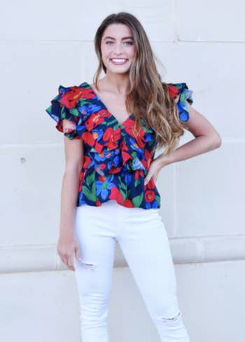 model in navy ruffle short sleeve blouse with red green orange and blue flowers