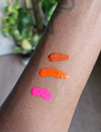 Three swatches of different lipsticks are shown on a forearm for color comparison