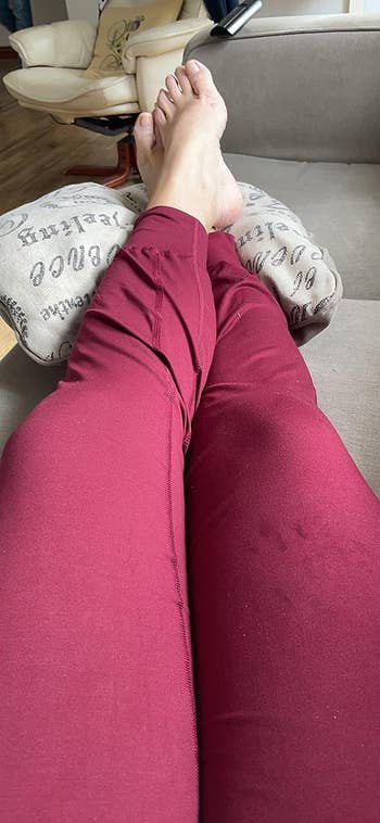 another reviewer taking a photo of themselves wearing the burgundy joggers while seated