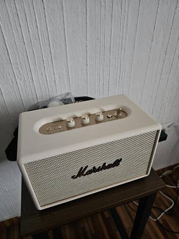 Speaker connected a table, featuring 4 knobs and a marque logo