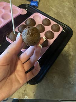 reviewer holding up a cake ball made from the mold