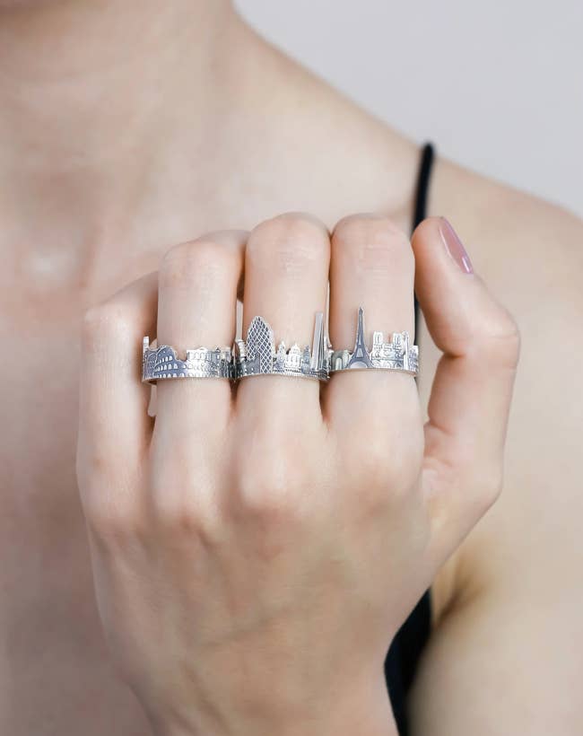 Model wearing three silver cityscape rings