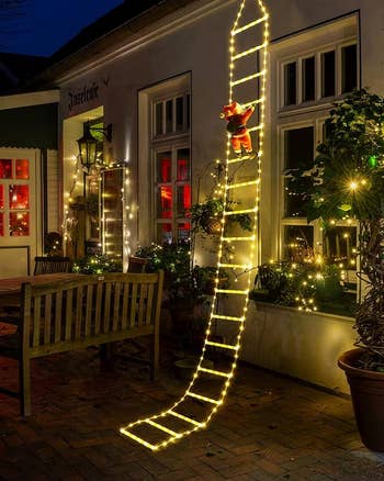 The ladder with warm white lights hanging off the side of a house