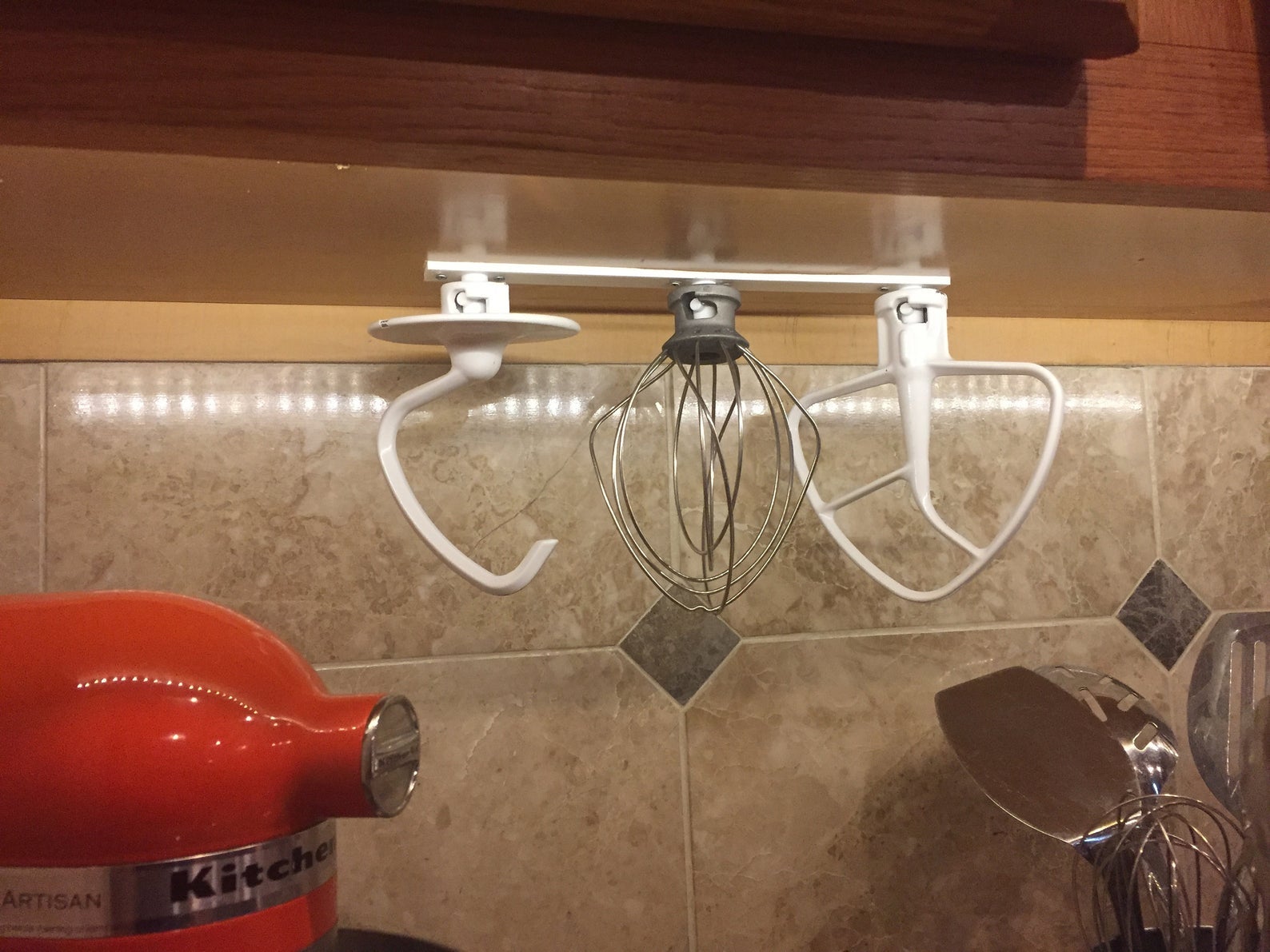 the attachment organizer hanging underneath a kitchen cabinet with three attachments on it