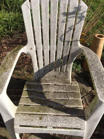 a reviewer photo of a plastic lawn chair covered in black mold and mildew 