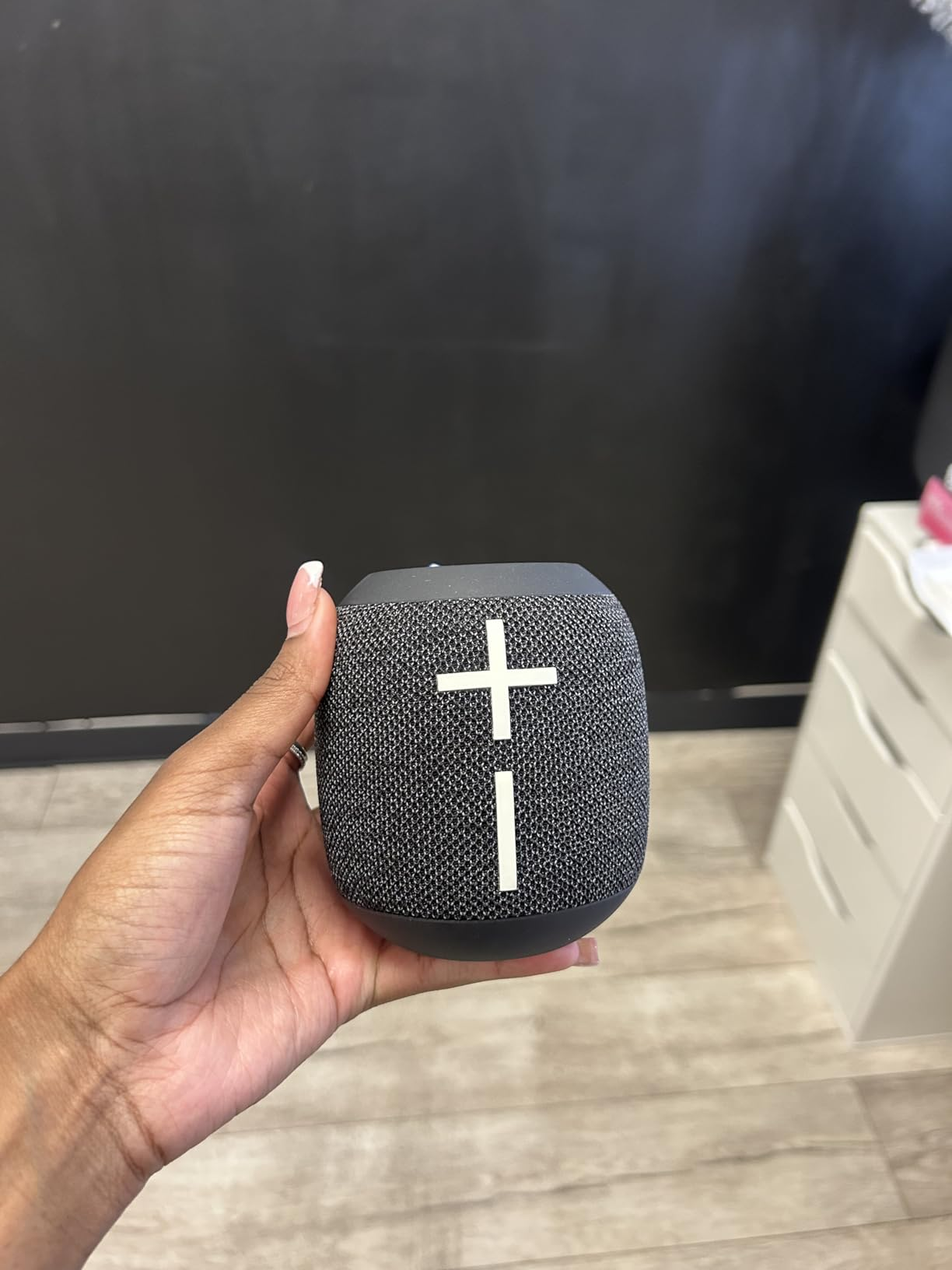 A idiosyncratic   holds a tiny  portable Bluetooth talker  with power  buttons connected  top, suitable for on-the-go euphony  listening