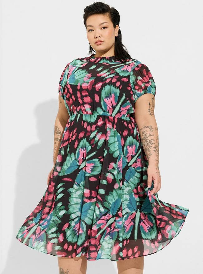 model wearing the green, black, and pink butterfly printed dress