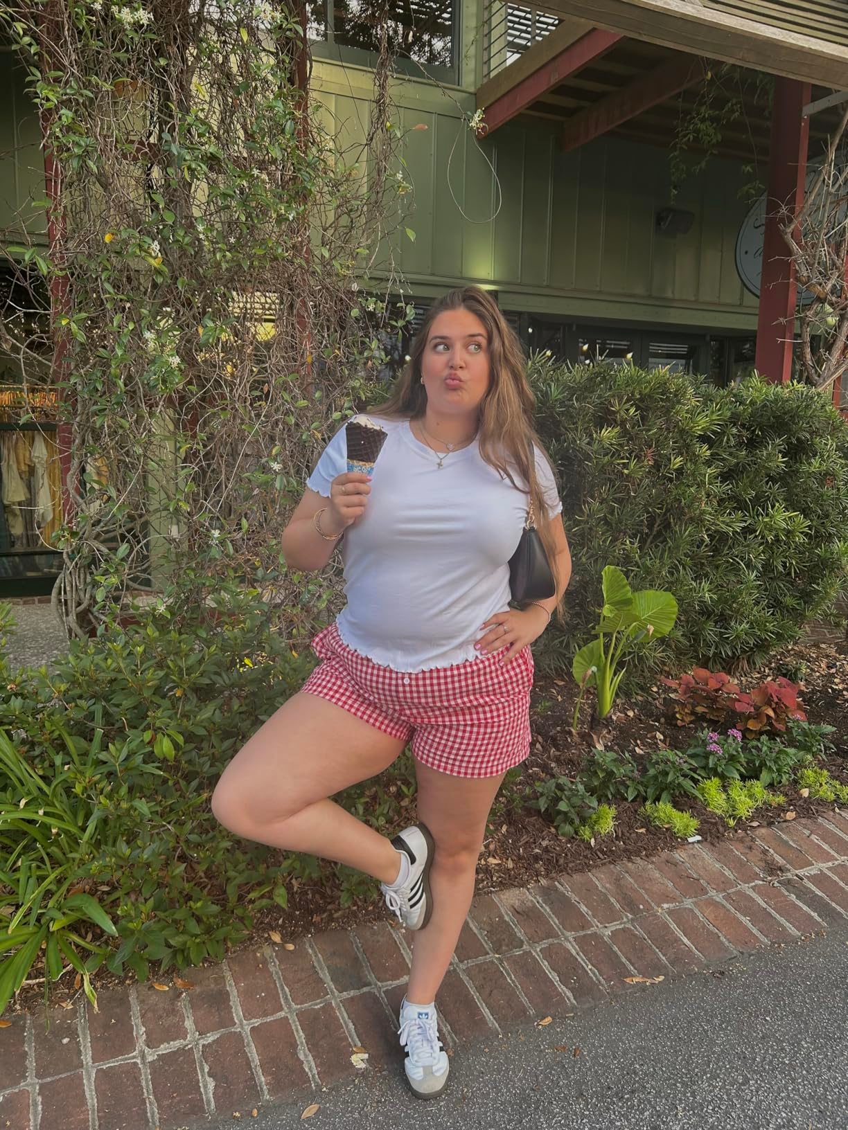 Person successful  casual achromatic  t-shirt and checkered shorts, holding an crystal  pick  cone, lasting  outdoors with a playful expression