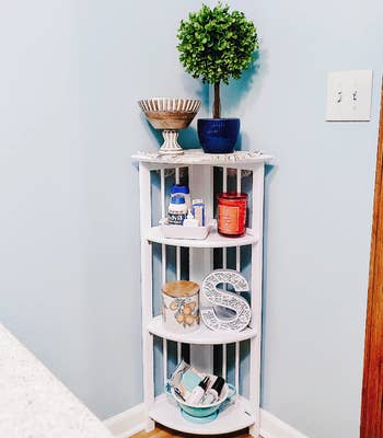 Reviewer image of white corner bookshelf with candles and toiletries on each shelf