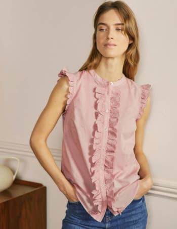 model in pink sleeveless top with embroidered ruffles at shoulder and placket