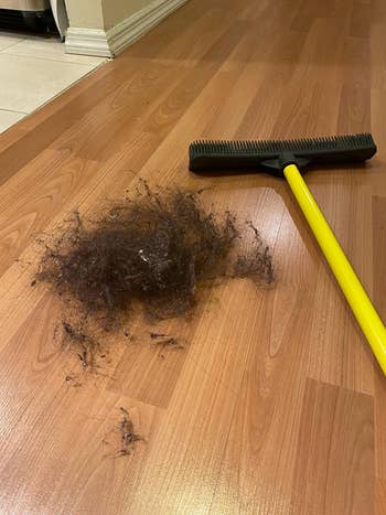 the same broom next to giant pile of black dog fur on floor