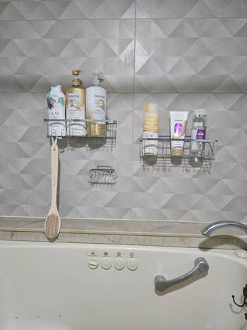 Various bath products and a brush hang on a geometric-patterned bathroom wall, above a tub with control buttons