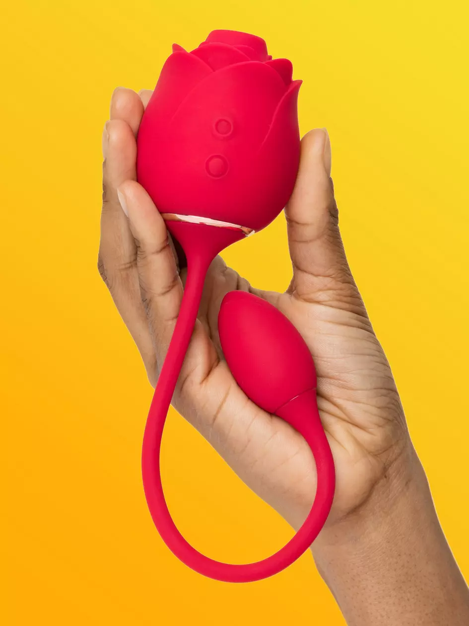 Hand holding a rose-shaped menstrual cup against a yellow background, for shopping guide