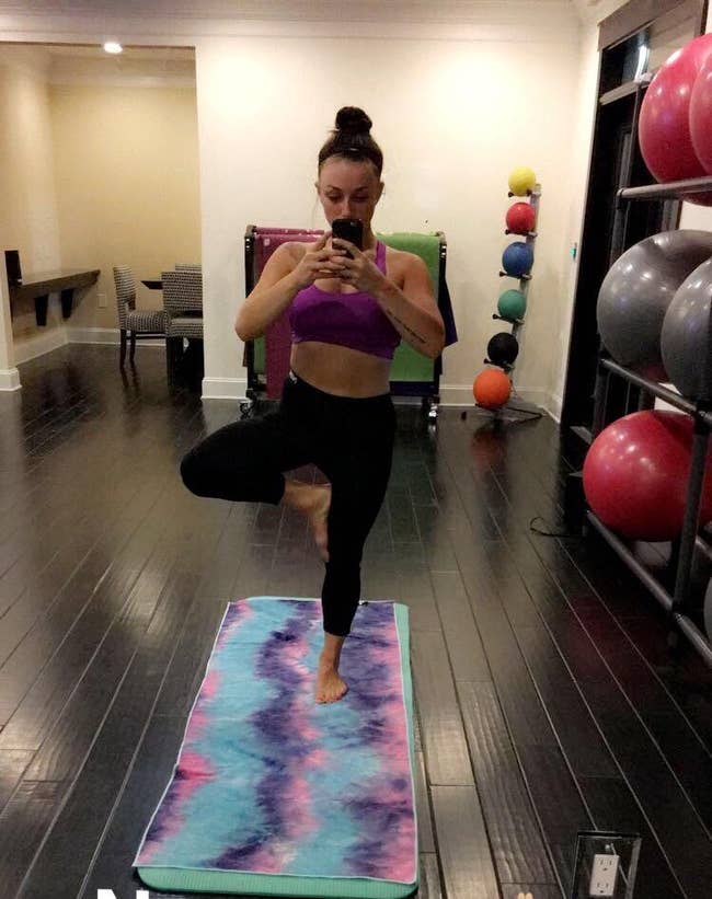 Reviewer practices a balance move while doing yoga on the same tie-dye towel