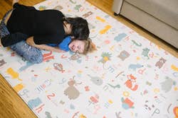 Parent and child playing on a playful, illustrated animal mat