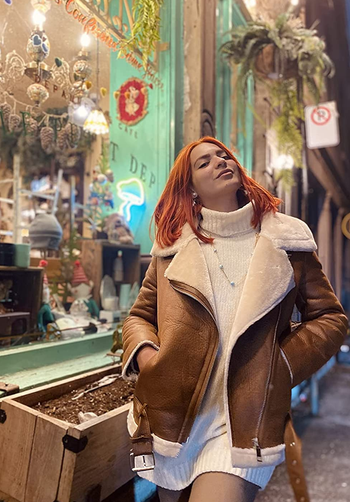 reviewer wearing the brown fleece lined moto jacket with a sweater dress