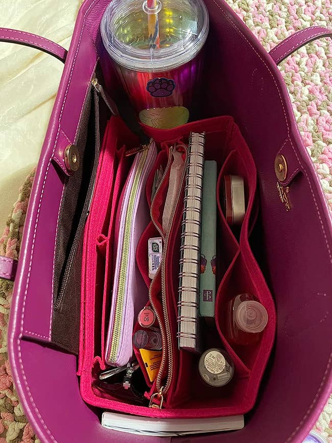 The pink bag organizer inside of a reviewer's bag holding books, lipsticks, and more