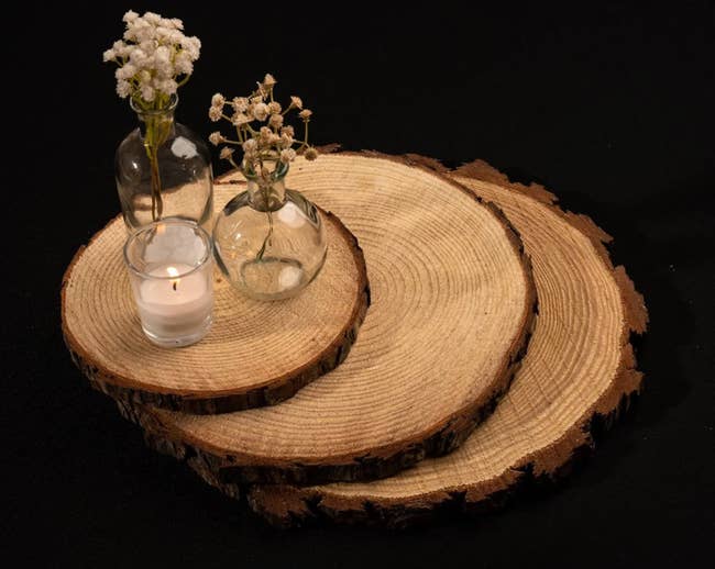 Three wooden slices stacked with jars and a candle on top