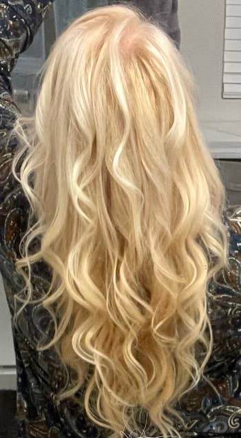 Person standing with their back toward the camera, showcasing long wavy blonde hair