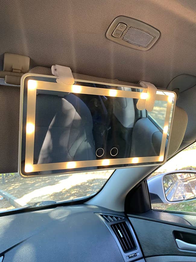 a reviewer's white mirror lit up and attached to their car's sun visor
