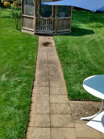 Brick pathway leads to a woody  gazebo successful  a grassy yard, with a circular  array  partially disposable   successful  the foreground