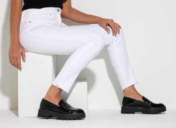 Model sitting down and wearing the loafers in black