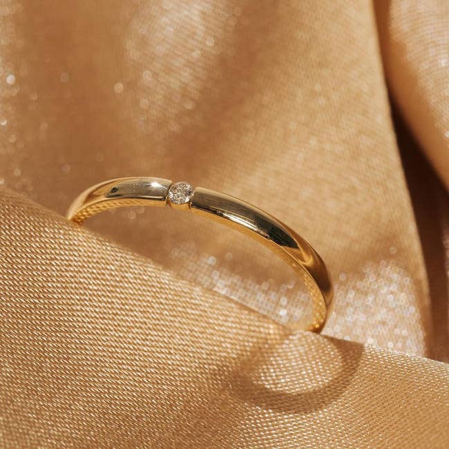 a thin gold band with a small circle diamond in the middle