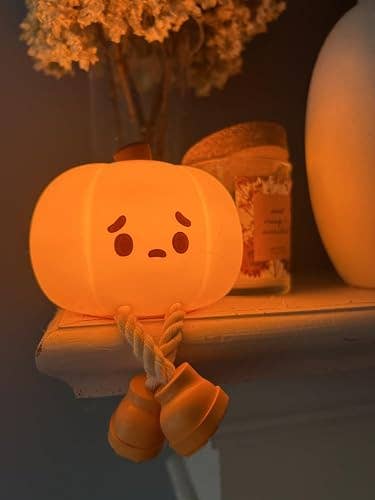 A cute, worried-faced pumpkin decoration with dangling enactment      legs sits connected  a shelf, adding a whimsical interaction   to location  décor for the autumn  season