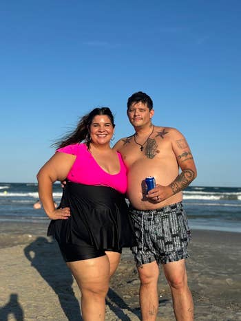 A smiling mates  connected  a beach, with the pistillate   successful  a stylish swimsuit formal  and the antheral   successful  aquatics  trunks, some  enjoying a sunny time  by the sea