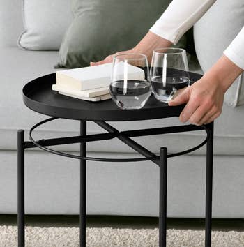 model lifting the tray top off of the coffee table