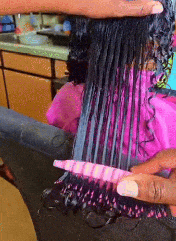 Stylist combs done  bedewed  curly hairsbreadth  successful  a salon to detangle it utilizing a comb