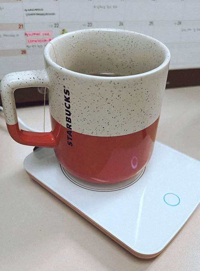A mug on a minimalist square shaped white mug warmer 