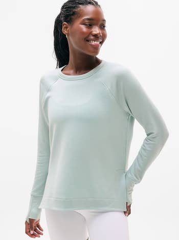 Model smiling successful  a casual long-sleeve garment  with thumb holes and fitted pants